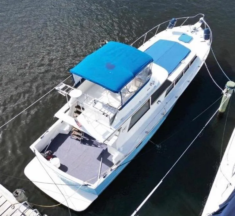Slide: The Image of 1985 Roughwater 36 boat with blue canopy, docked on calm water. - 4