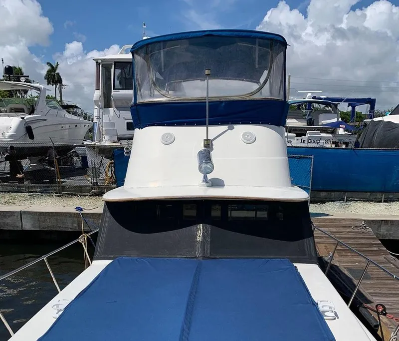 Slide: The Image of 1985 Roughwater 36 boat docked, featuring blue and white design under a clear sky. - 5