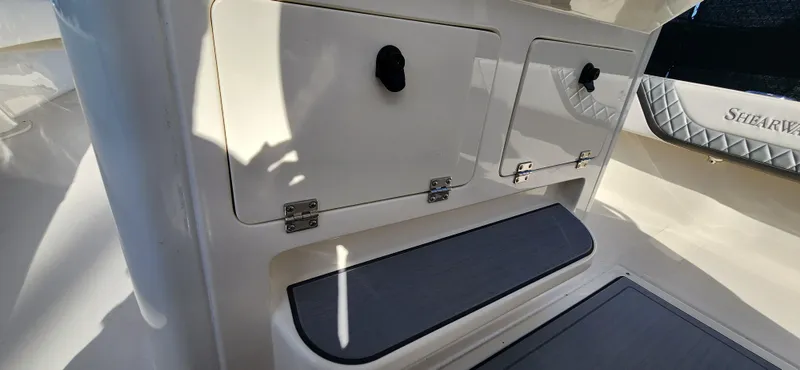 Slide: The Image of 2025 ShearWater 270 SS Open Carolina boat interior with storage compartments and cushioned step. - 17