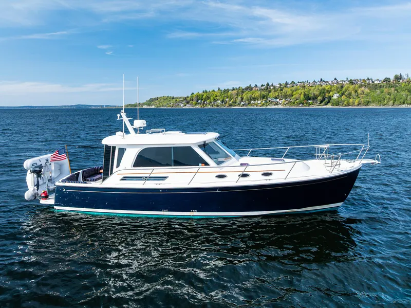 Slide: The Image of 2013 Back Cove 37 yacht cruising on a serene blue lake under a clear sky. - 1