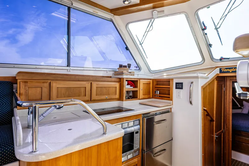 Slide: The Image of Interior of 2013 Back Cove 37 yacht, featuring modern kitchen with wood cabinetry and stainless appliances. - 29