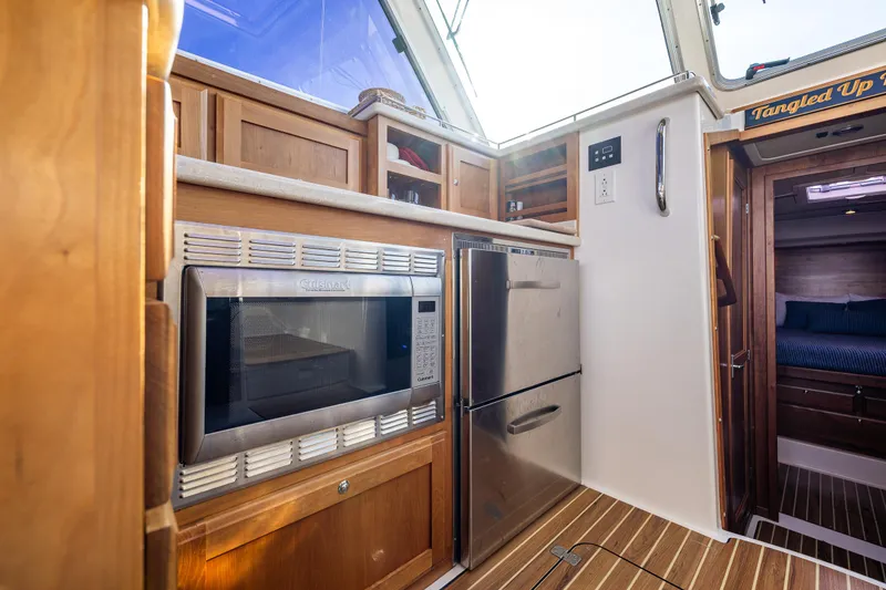Slide: The Image of 2013 Back Cove 37 yacht kitchen with microwave, fridge, and wooden cabinetry. - 30