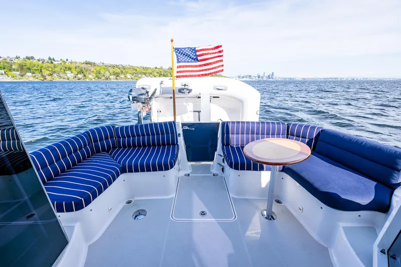 Slide: The Image of 2013 Back Cove 37 boat with striped seating, American flag, and scenic water view. - 33