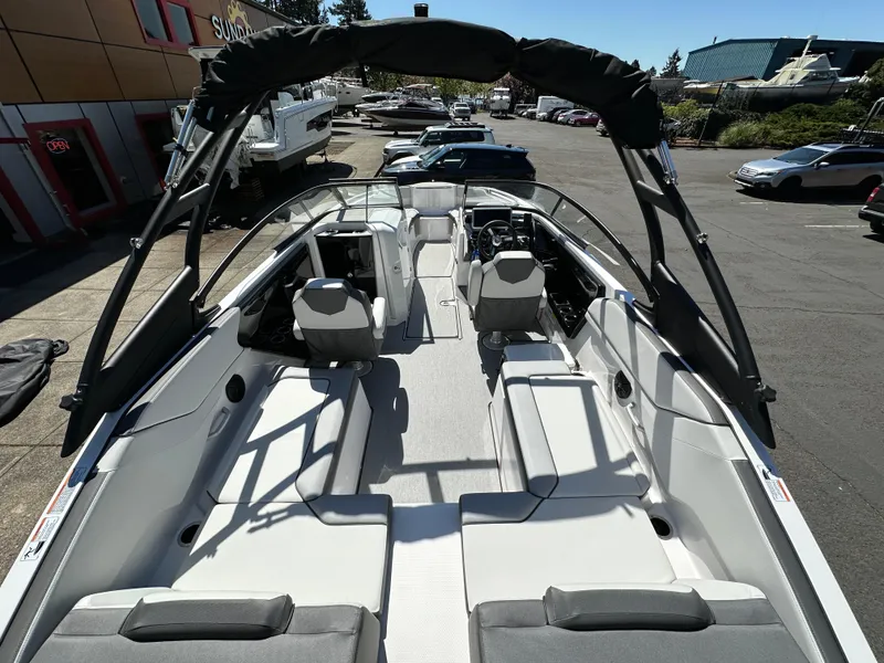 Slide: The Image of 2024 Yamaha Boats AR250 interior with seating and helm, parked outdoors. - 15