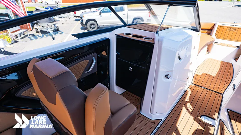 Slide: The Image of 2025 Yamaha Boats 252SD interior with brown seating and wood flooring at Long Lake Marina. - 10