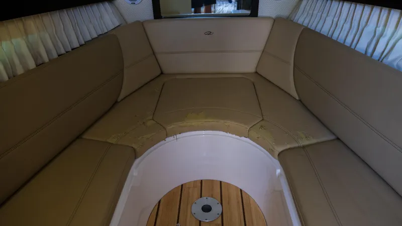 Slide: The Image of Interior seating area of 2013 Regal 28 Express boat with beige cushions. - 18