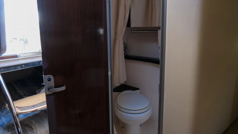 Slide: The Image of 2013 Regal 28 Express boat bathroom interior with toilet and wooden door. - 22