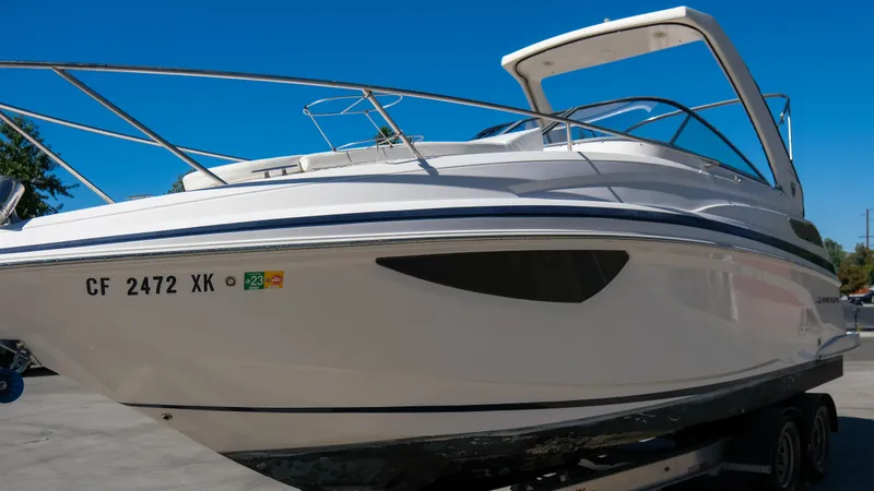 Slide: The Image of 2013 Regal 28 Express boat on trailer, side view under clear blue sky. - 24