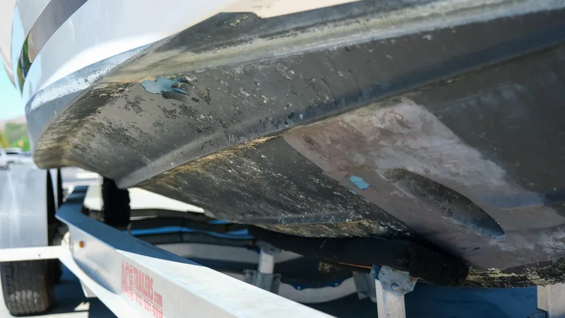 Slide: The Image of 2013 Regal 28 Express boat hull on trailer, showing wear and damage. - 4