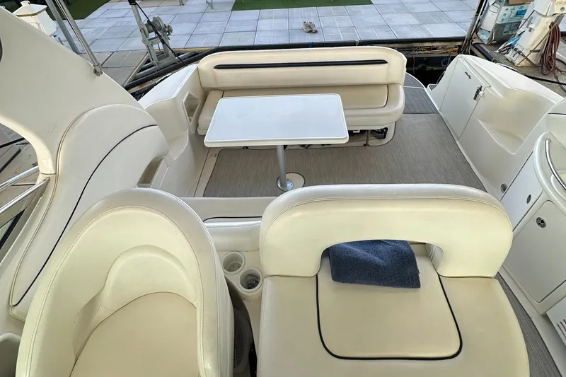 Slide: The Image of 2006 Sea Ray 360 Sundancer cockpit with seating and table, featuring elegant white upholstery. - 24