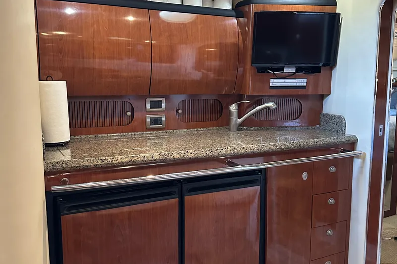 Slide: The Image of 2006 Sea Ray 360 Sundancer yacht kitchen with wood cabinetry, granite countertop, and mounted TV. - 29