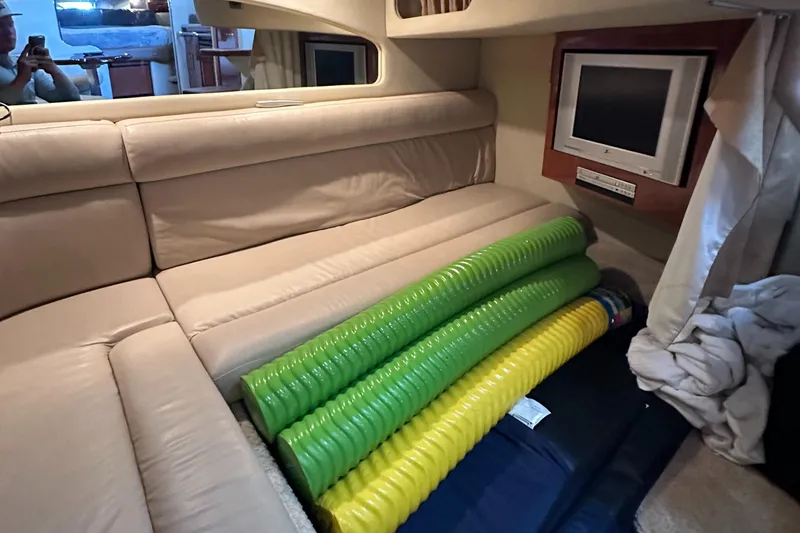 Slide: The Image of 2006 Sea Ray 360 Sundancer cabin with beige seating, colorful pool noodles, and a wall-mounted TV. - 36