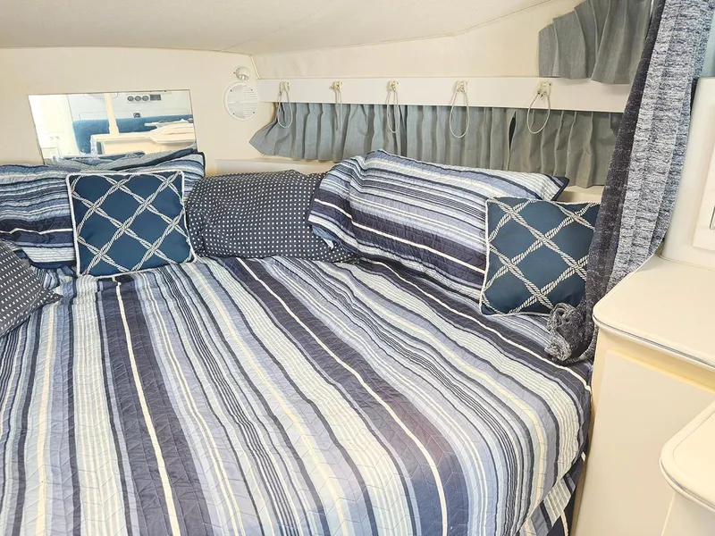 Slide: The Image of 1995 Wellcraft 330 Coastal cabin interior with striped bedding and decorative pillows. - 25