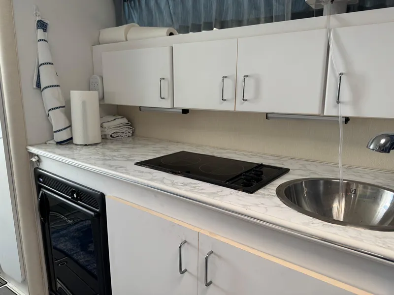 Slide: The Image of 1995 Wellcraft 330 Coastal boat kitchen with stove, sink, and white cabinets. - 27