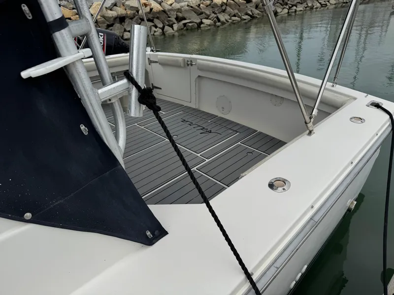 Slide: The Image of 1995 Wellcraft 330 Coastal boat deck with black rope, docked near rocky shoreline. - 5