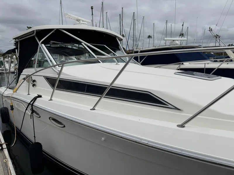 Slide: The Image of 1995 Wellcraft 330 Coastal boat docked at marina, overcast sky, sleek white design. - 7