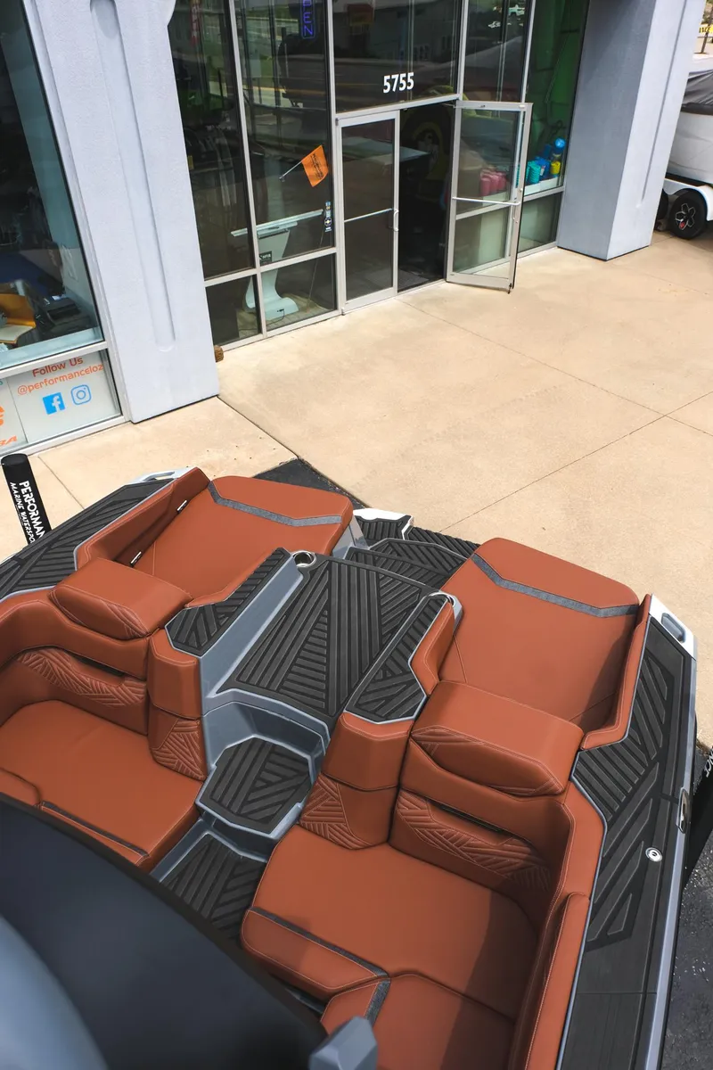 Slide: The Image of 2025 MasterCraft XStar 25 boat with luxurious brown seating, parked outside a showroom. - 20