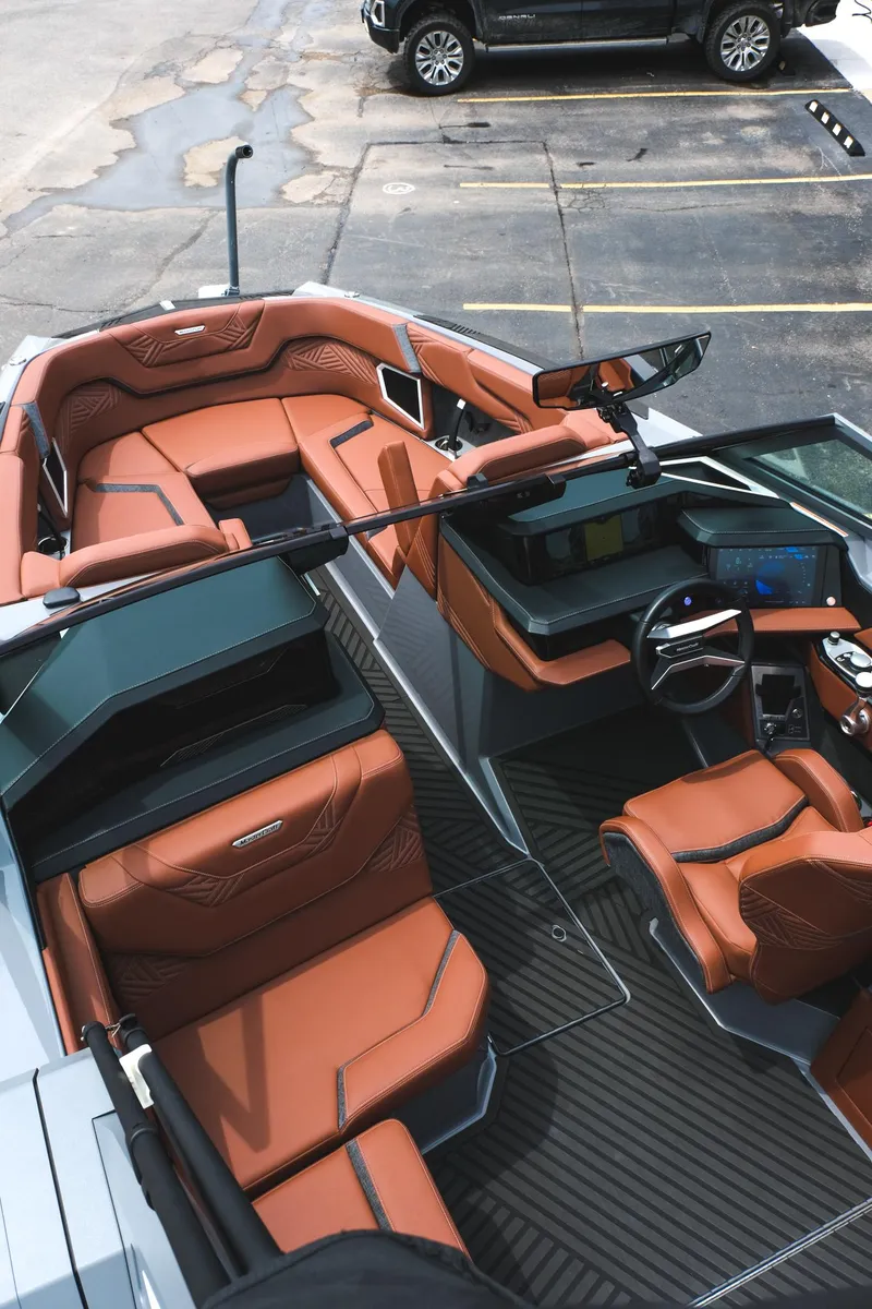 Slide: The Image of 2025 MasterCraft XStar 25 boat interior with luxurious brown seating and modern dashboard. - 23