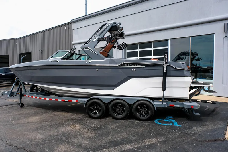 Slide: The Image of 2025 MasterCraft XStar 25 boat on trailer, parked outside a building. - 3