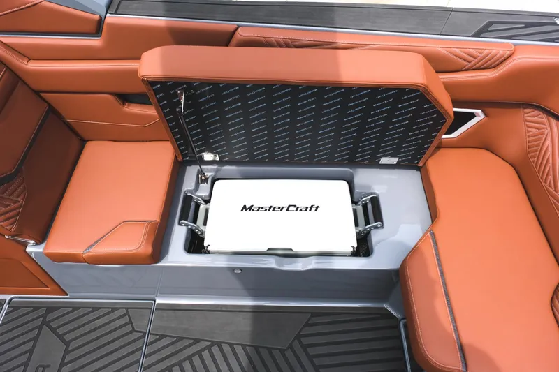 Slide: The Image of 2025 MasterCraft XStar 25 boat interior with open storage compartment and orange seating. - 34