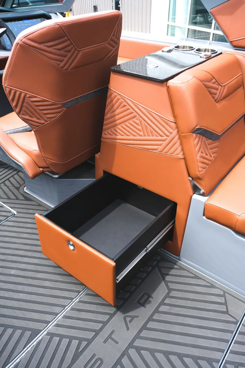 Slide: The Image of 2025 MasterCraft XStar 25 interior with open storage drawer and luxurious brown seating. - 38