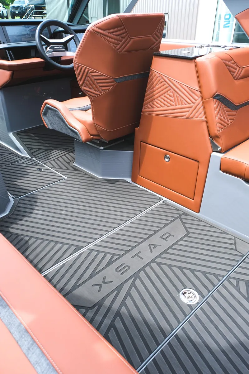 Slide: The Image of 2025 MasterCraft XStar 25 interior with brown seats and sleek black flooring. - 39