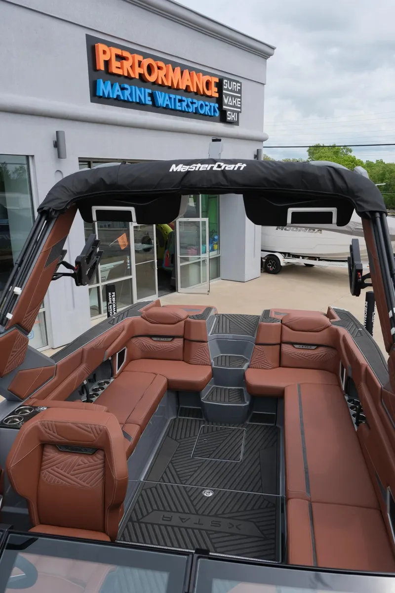 Slide: The Image of 2025 MasterCraft XStar 25 boat with brown seating at Performance Marine Watersports dealership. - 47