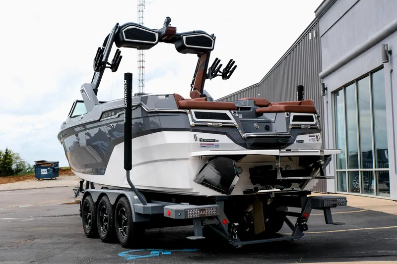 Slide: The Image of 2025 MasterCraft XStar 25 boat on trailer, parked outside a building. - 9
