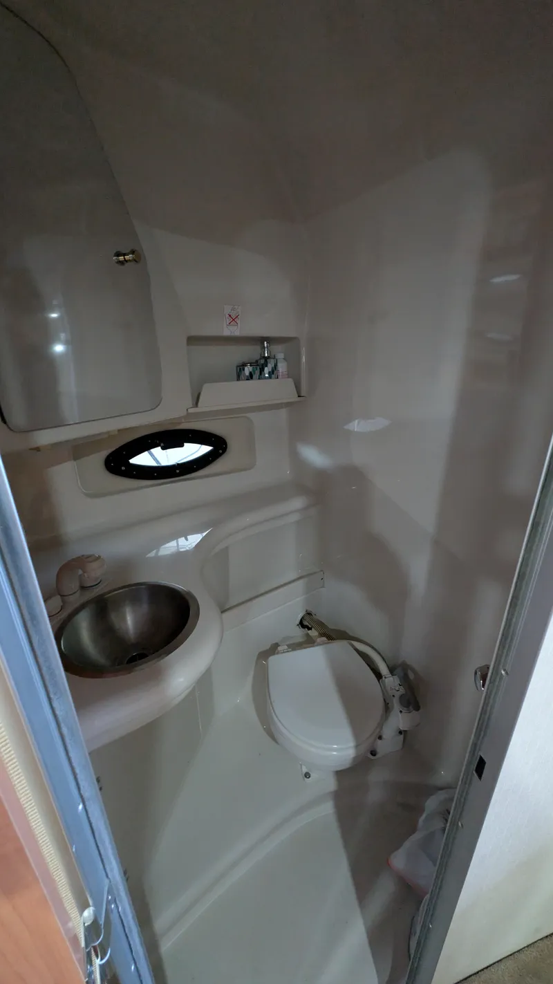Slide: The Image of Compact bathroom in a 2000 Regal 2860 Commodore boat, featuring a sink and toilet. - 23
