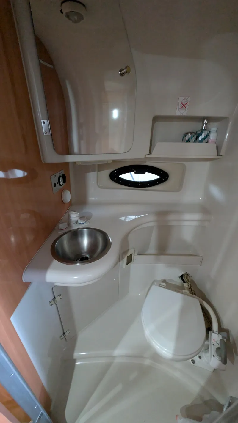 Slide: The Image of 2000 Regal 2860 Commodore boat bathroom with sink, toilet, and porthole window. - 24