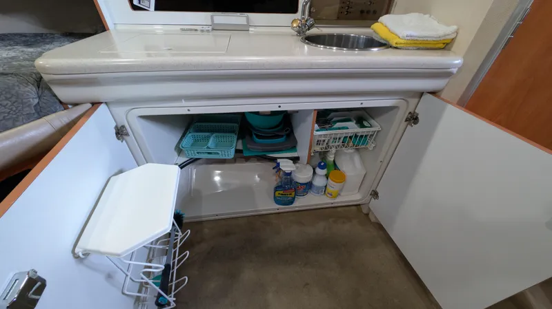 Slide: The Image of 2000 Regal 2860 Commodore kitchen area with open cabinet, sink, and cleaning supplies. - 25