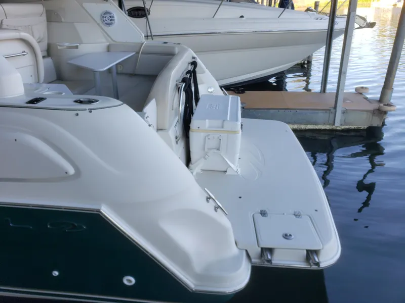 Slide: The Image of 2000 Regal 2860 Commodore boat docked, featuring a spacious swim platform and seating area. - 8