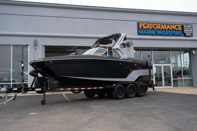 Slide: The Image of 2025 MasterCraft XStar 23 boat on trailer outside Performance Marine Watersports store. - 1