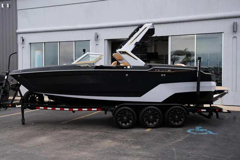 Slide: The Image of 2025 MasterCraft XStar 23 boat on trailer, sleek black and white design. - 2