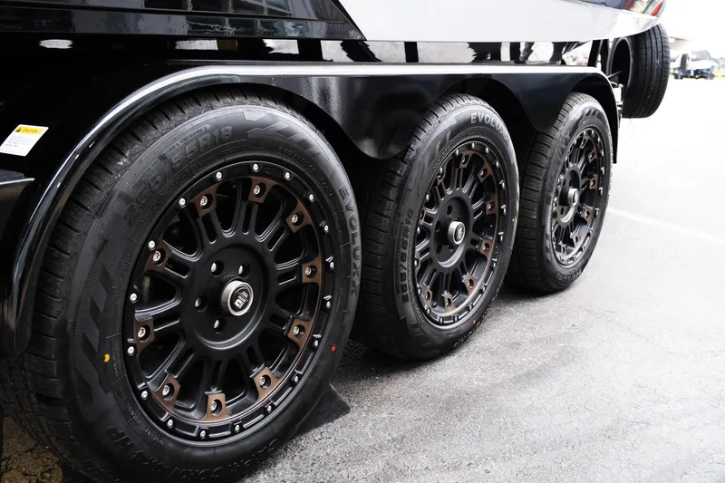 Slide: The Image of 2025 MasterCraft XStar 23 trailer with sleek black wheels on pavement. - 41