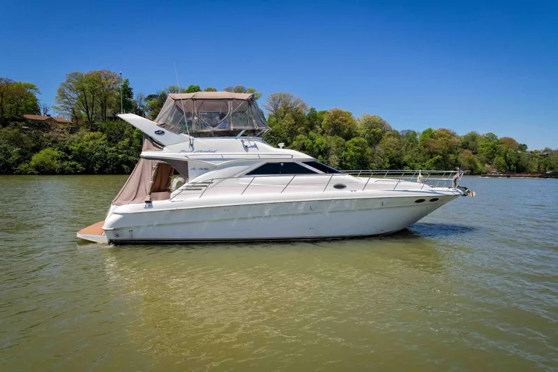 Slide: The Image of 1998 Sea Ray 400 Sedan Bridge yacht on calm water, surrounded by lush greenery. - 1