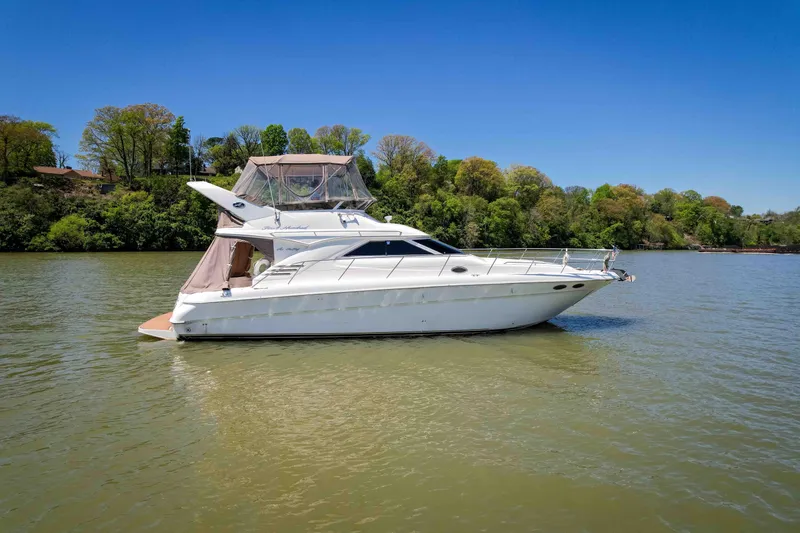 Slide: The Image of 1998 Sea Ray 400 Sedan Bridge yacht on calm water, surrounded by lush greenery. - 12