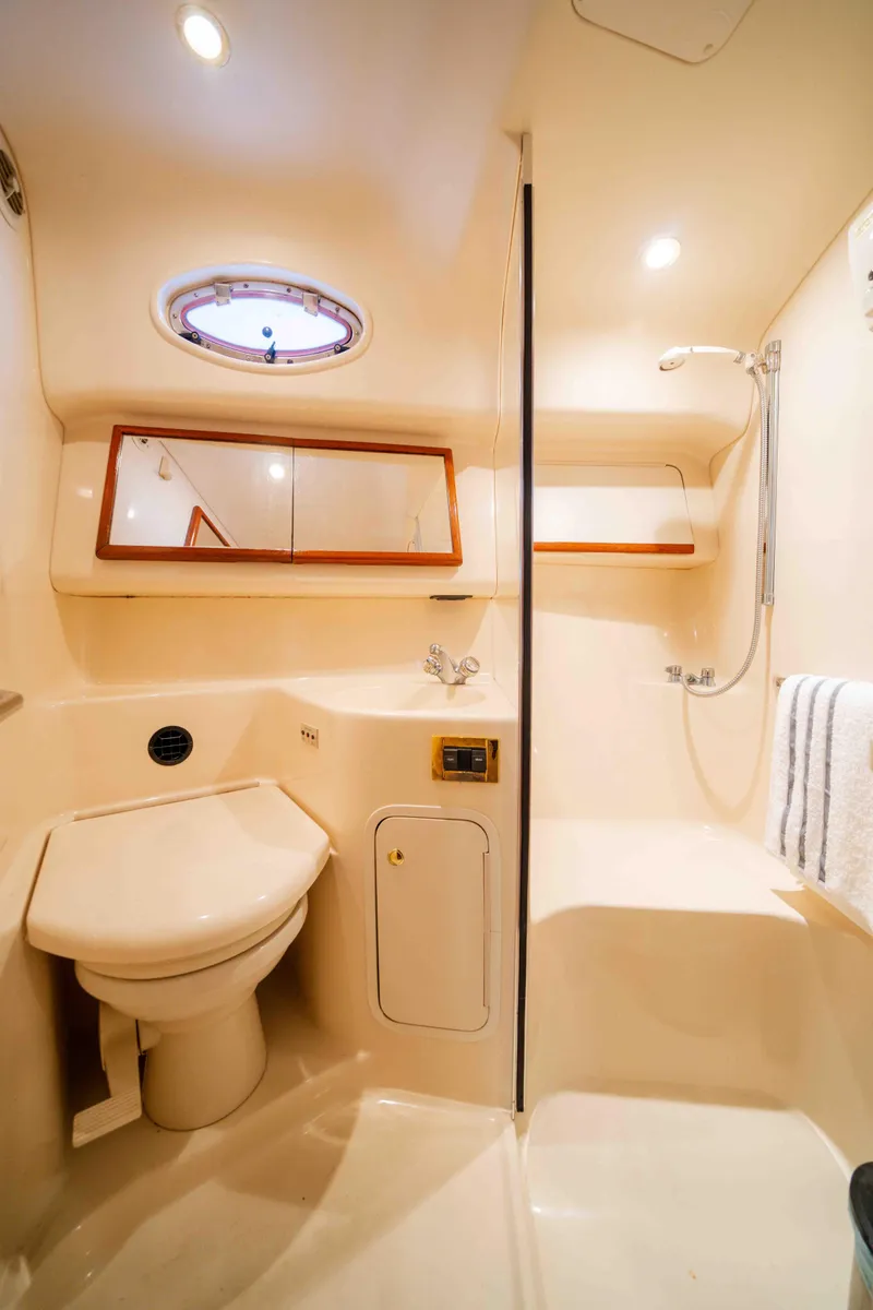 Slide: The Image of 1998 Sea Ray 400 Sedan Bridge bathroom with shower, toilet, and porthole window. - 17