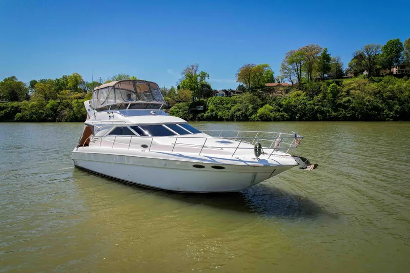 Slide: The Image of 1998 Sea Ray 400 Sedan Bridge yacht on a calm river with lush green trees. - 2