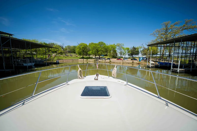 Slide: The Image of Bow view of 1998 Sea Ray 400 Sedan Bridge docked in a serene marina. - 27