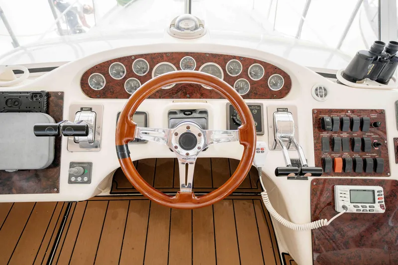 Slide: The Image of 1998 Sea Ray 400 Sedan Bridge helm with wood steering wheel and control panel. - 34
