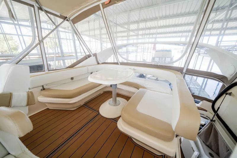 Slide: The Image of 1998 Sea Ray 400 Sedan Bridge interior with cushioned seating and table, featuring wood-style flooring. - 39