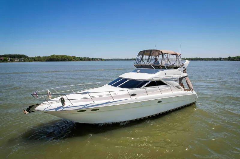 Slide: The Image of 1998 Sea Ray 400 Sedan Bridge yacht cruising on a calm lake under clear blue skies. - 4