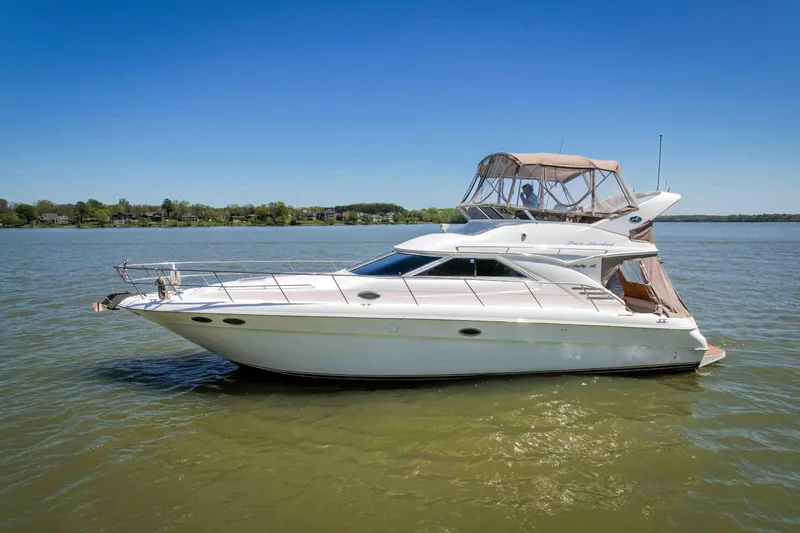 Slide: The Image of 1998 Sea Ray 400 Sedan Bridge yacht on calm water under clear blue sky. - 5