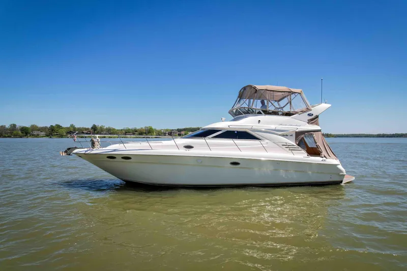 Slide: The Image of 1998 Sea Ray 400 Sedan Bridge yacht on calm water under clear blue sky. - 6