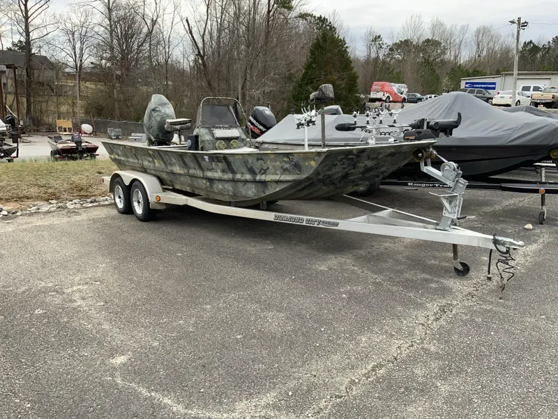 Slide: The Image of 2006 War Eagle 2072CC boat on trailer, parked outdoors, with camouflage design. - 1