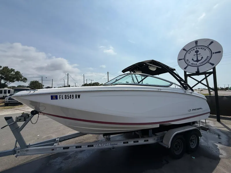 Slide: The Image of 2017 Regal 22 FasDeck boat on trailer, parked near nautical-themed sign. - 13