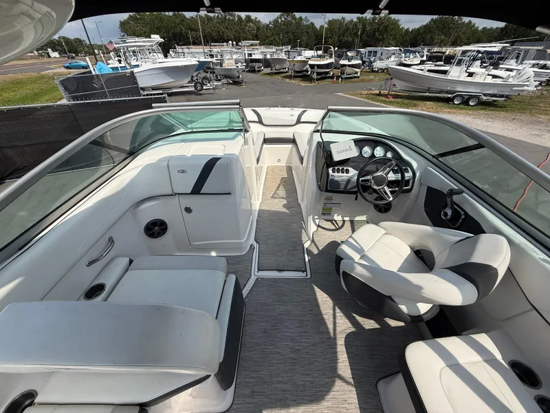 Slide: The Image of 2017 Regal 22 FasDeck boat interior with seating and steering wheel, docked among other boats. - 23