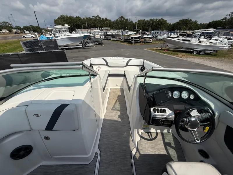 Slide: The Image of 2017 Regal 22 FasDeck boat interior with steering wheel and seating, parked in a marina. - 35