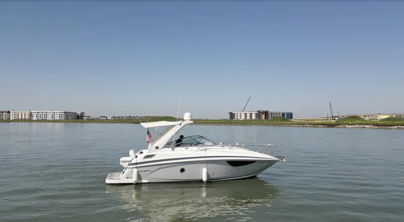 The Image of 2020 Regal 28 Express boat on calm water with buildings in the background. - 0
